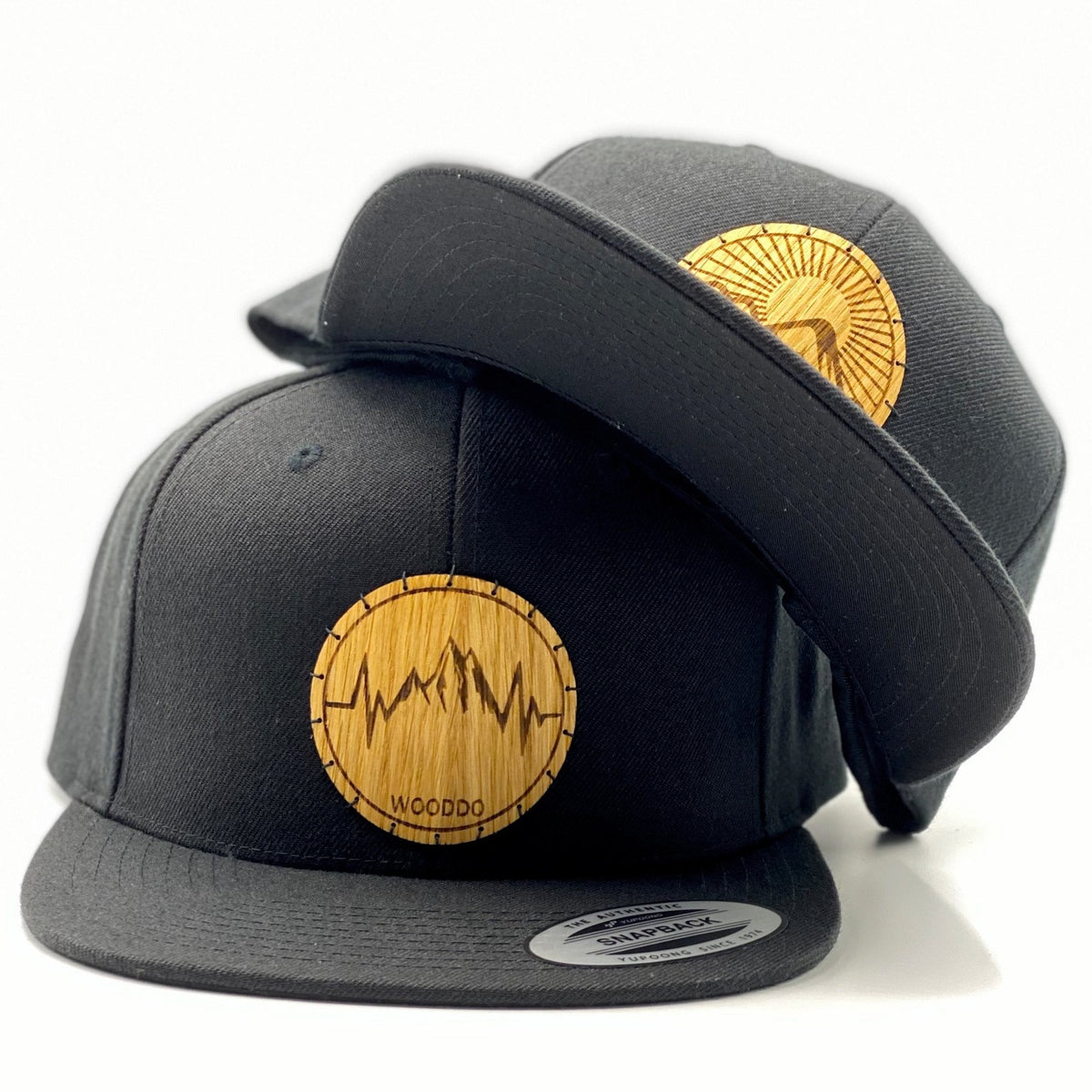 Schwarzes Natureclassic Snapback Cap mit Holzemblem Sunrise und Mountainheart, zwei Caps übereinander