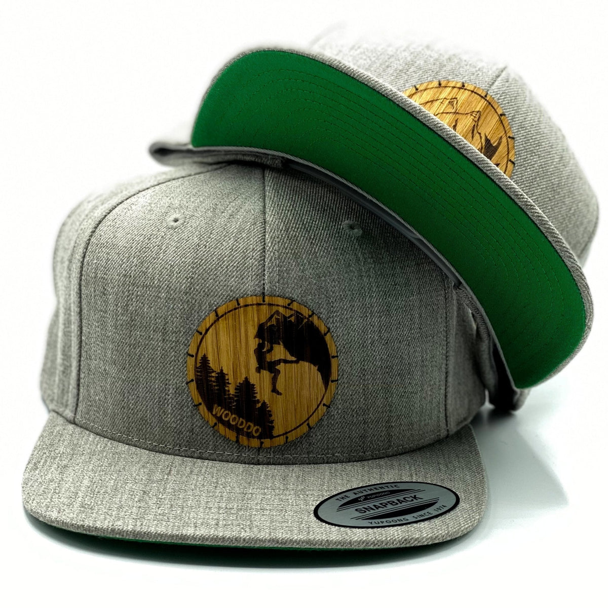 Hellgrau meliertes Natureclassic Snapback Cap mit Holzemblem Wild und Climber, zwei Caps übereinander